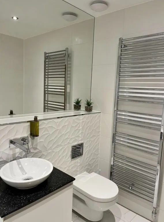 a bathroom with a sink and a toilet and a mirror at Royal Gardens Apartment 19 in Dornoch