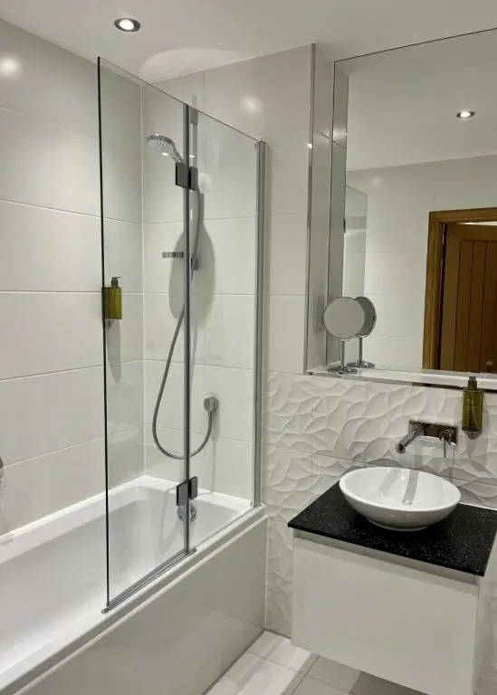 a white bathroom with a sink and a shower at Royal Gardens Apartment 19 in Dornoch