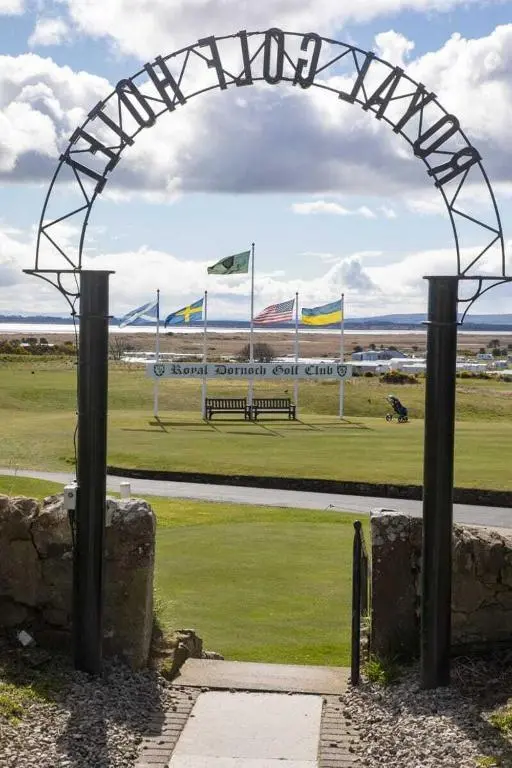 an arch over a park with a bench and flags at Royal Gardens Apartment 10 in Dornoch