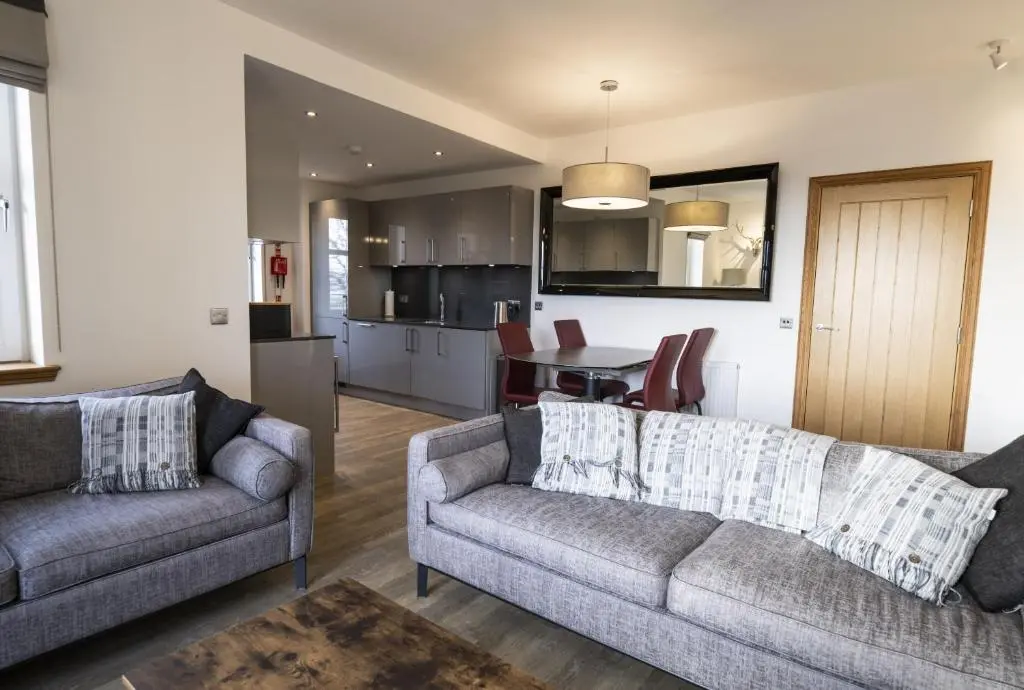 a living room with two couches and a kitchen at Royal Gardens Apartment 10 in Dornoch
