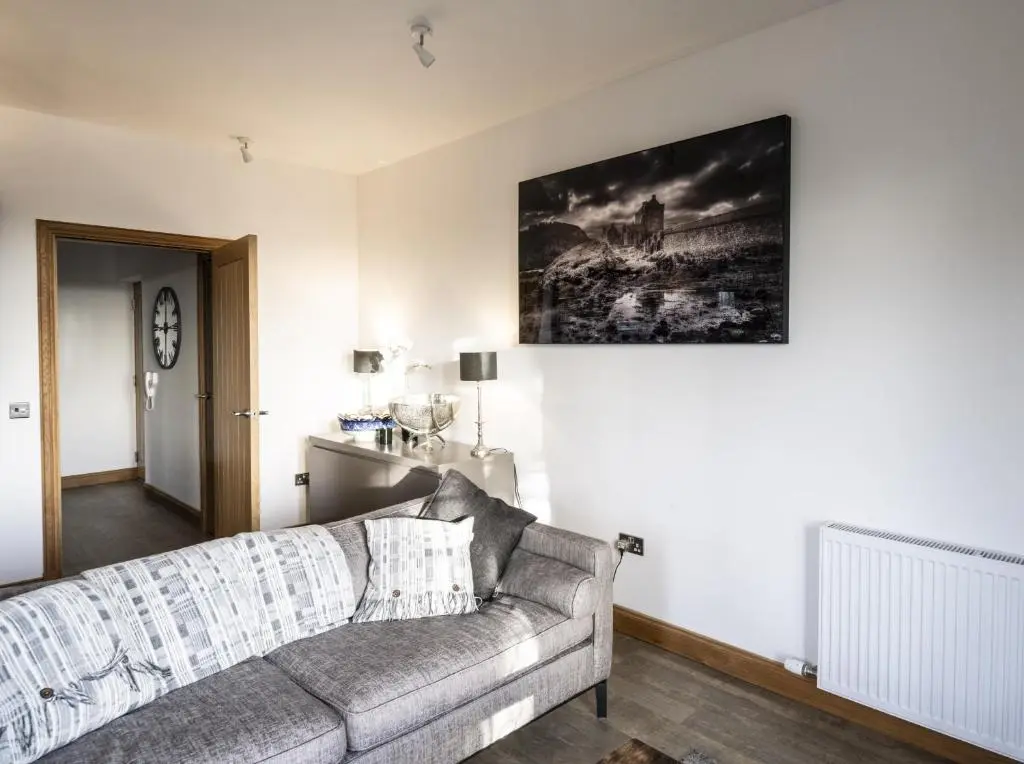 a living room with a couch and a painting on the wall at Royal Gardens Apartment 10 in Dornoch