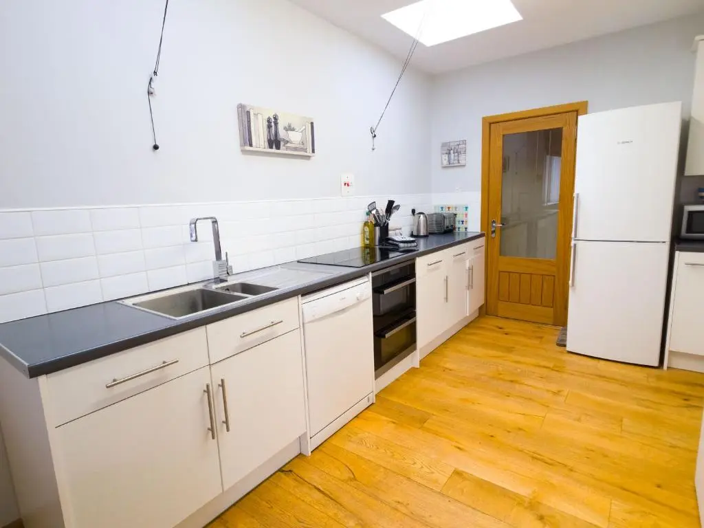a kitchen with white cabinets and a sink and a refrigerator at Loramore in Aviemore