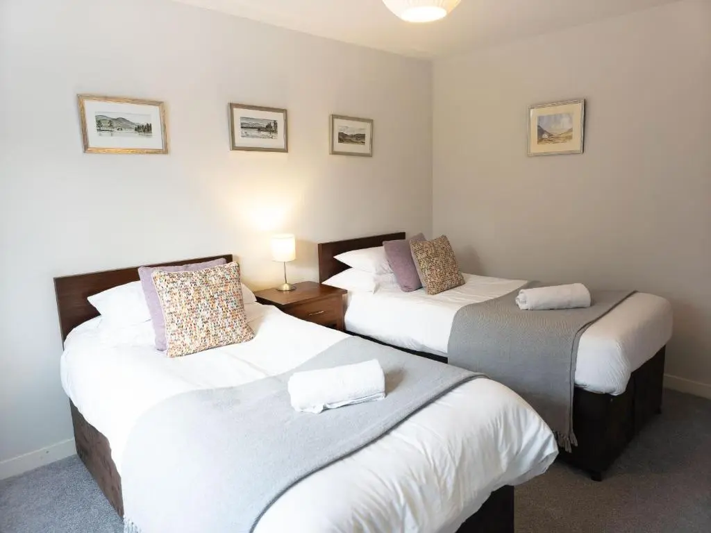 two beds in a room with white walls at Loramore in Aviemore