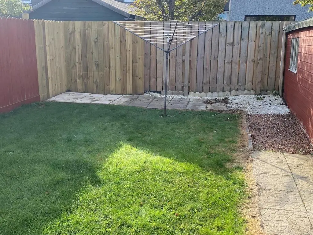 a backyard with a fence and a umbrella in the grass at Highland haven, free parking on driveway, near Raigmore Hospital in Inshes