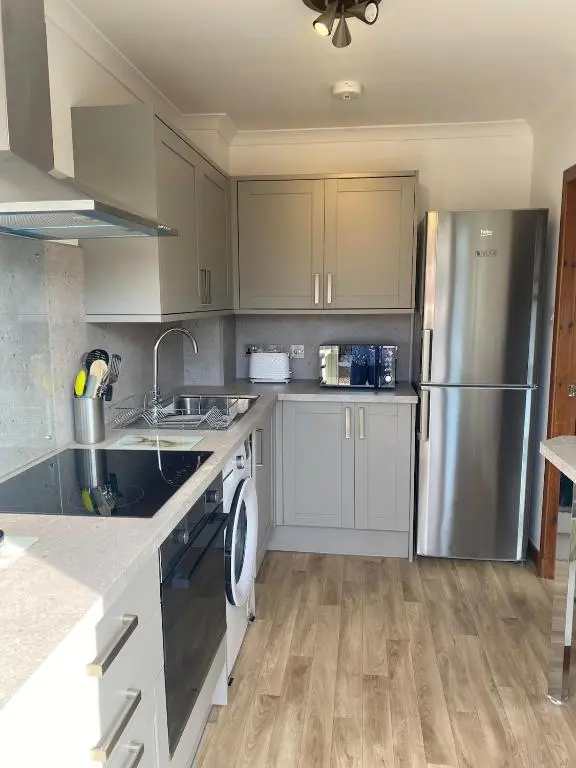 a kitchen with white cabinets and a stainless steel refrigerator at Highland haven, free parking on driveway, near Raigmore Hospital in Inshes