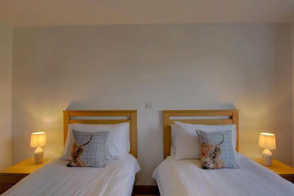 two beds with two dogs laying on the pillows at No8 The Links Apartment, Brora in Brora