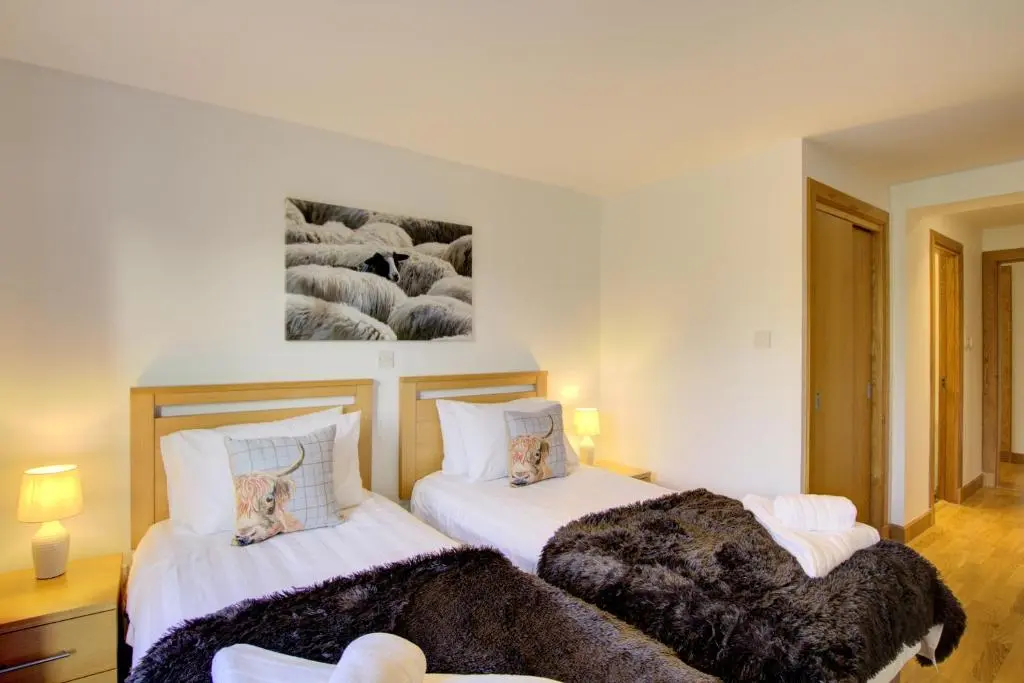 two beds in a room with white walls at No8 The Links Apartment, Brora in Brora