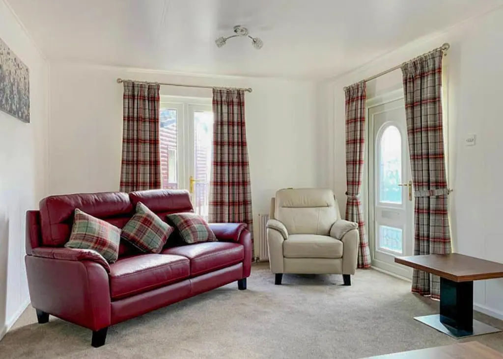 a living room with a red couch and a chair at Calvine Holiday Park in Pitlochry