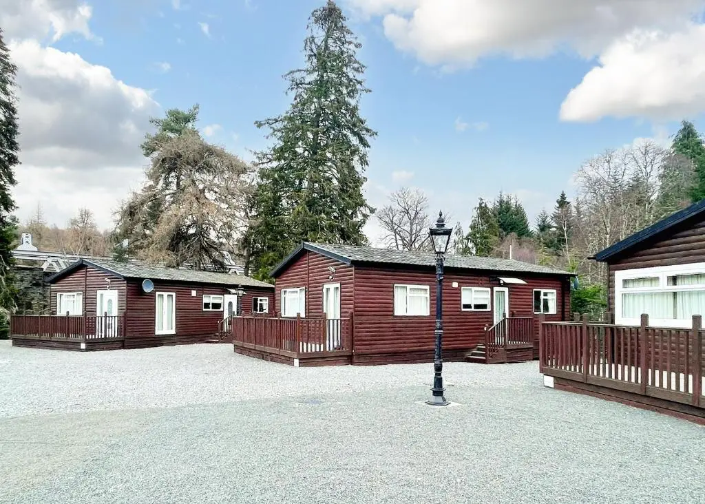 a group of wooden cabins in a parking lot at Calvine Holiday Park in Pitlochry
