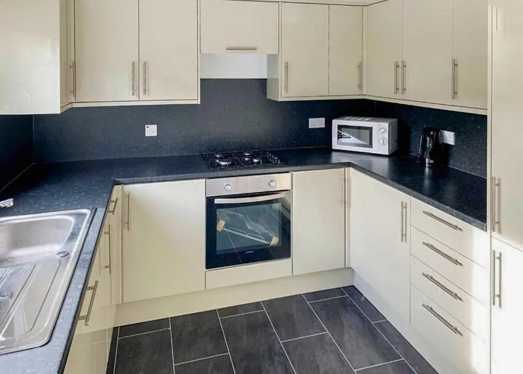 a kitchen with white cabinets and a stove and a microwave at Calvine Holiday Park in Pitlochry