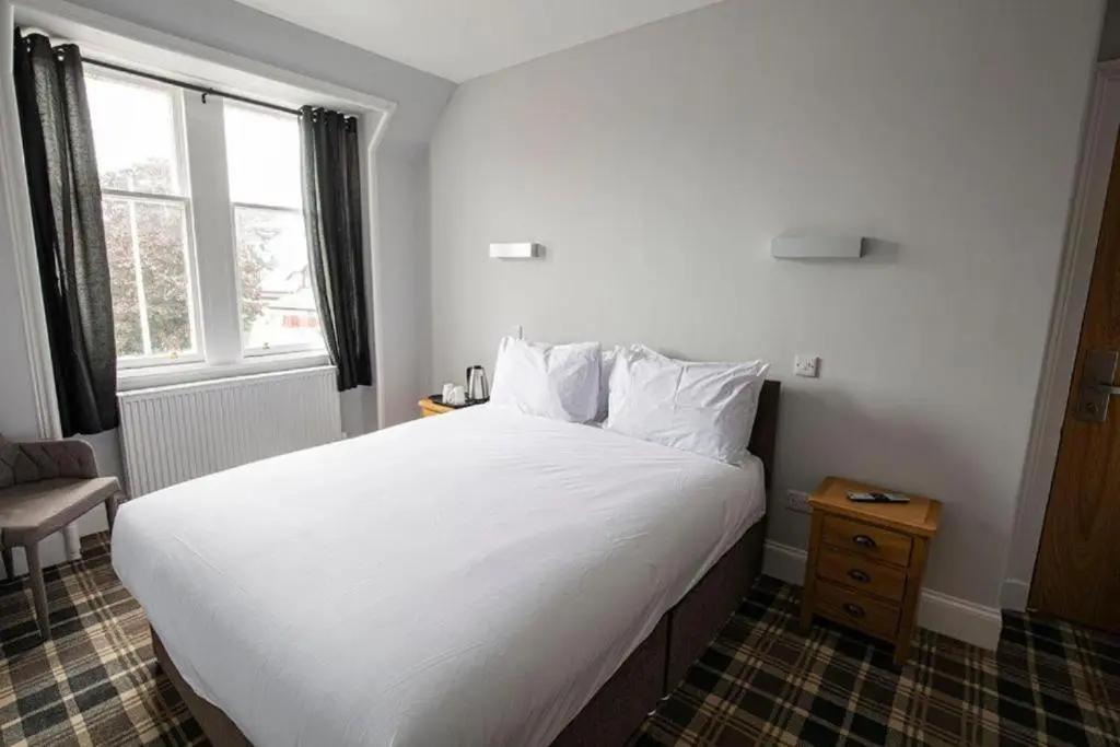 a bedroom with a large white bed with a window at Crown Hotel & Bar in Inverness