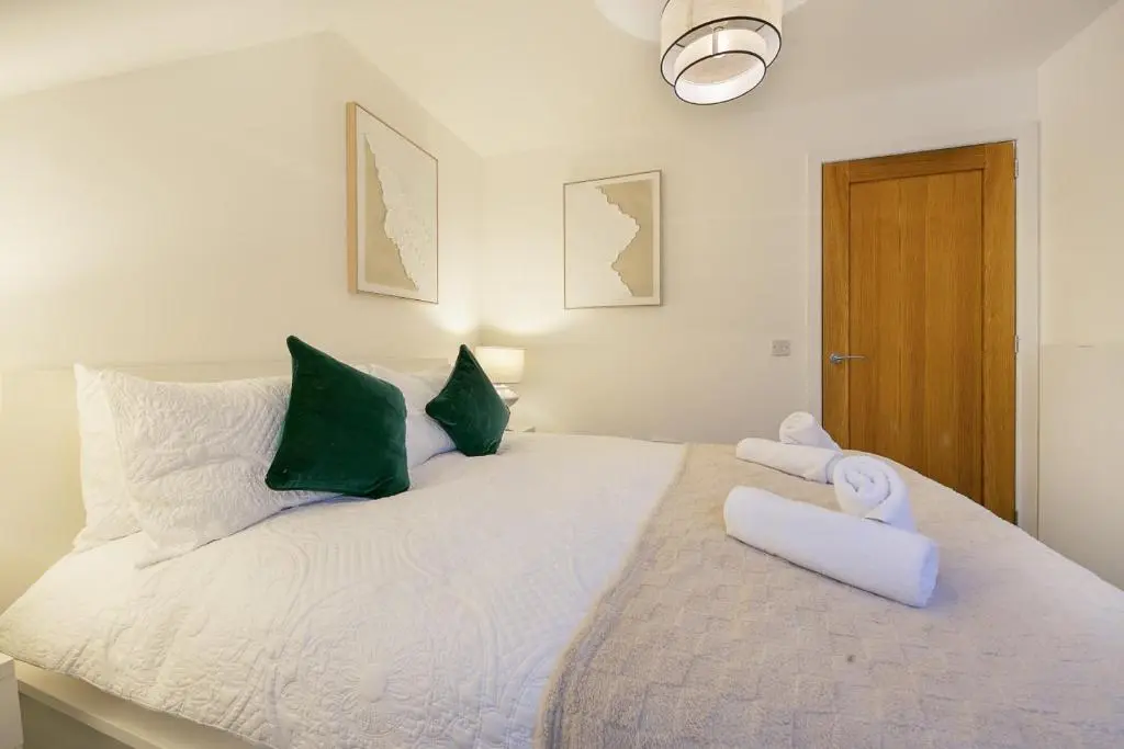 a bedroom with a large white bed with green pillows at Rooemah Lodge - Grampian Lettings in Caskieben