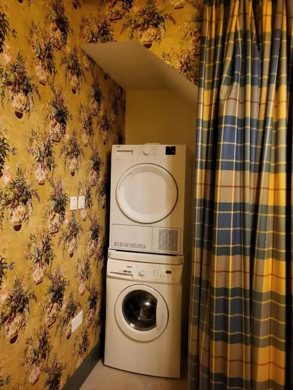 a washer and dryer in a room with a curtain at Gardeners Cottage