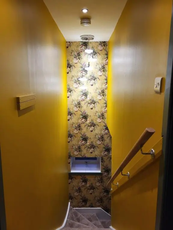 a hallway with yellow walls and stairs in a bathroom at Gardeners Cottage