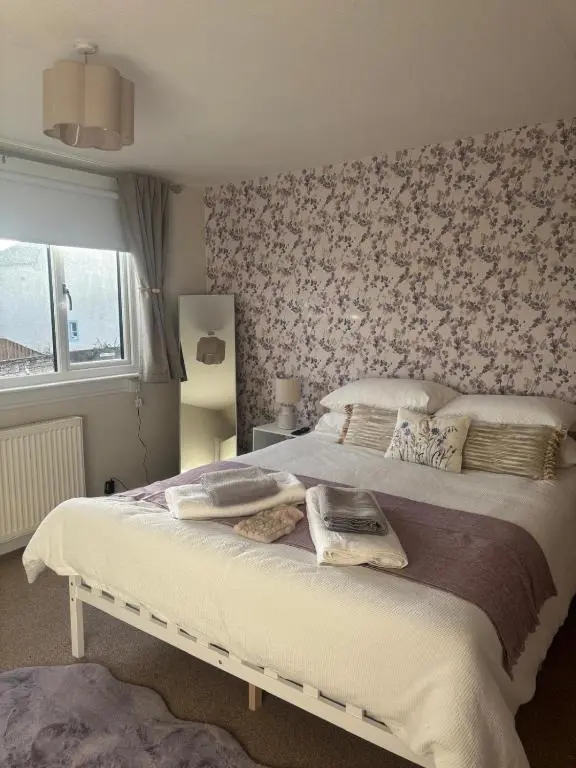a bedroom with a large bed with a floral wallpaper at Bluebell Cottage in Nairn