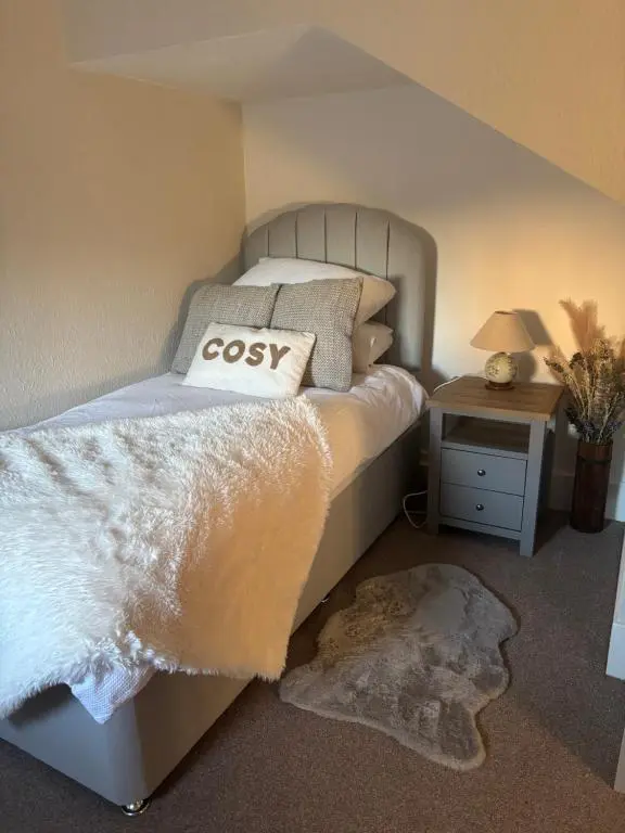 a bedroom with a bed with a cosy pillow on it at Bluebell Cottage in Nairn