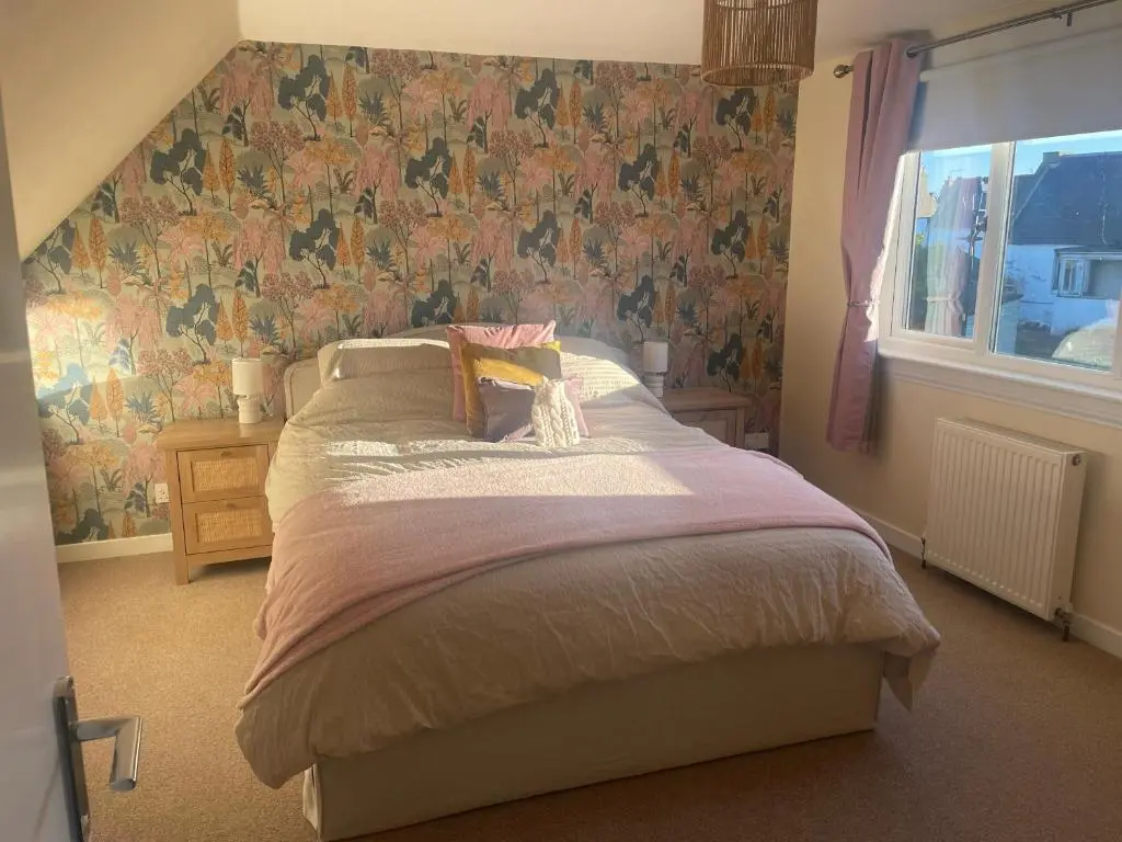 a bedroom with a bed with a floral wallpaper at Bluebell Cottage in Nairn