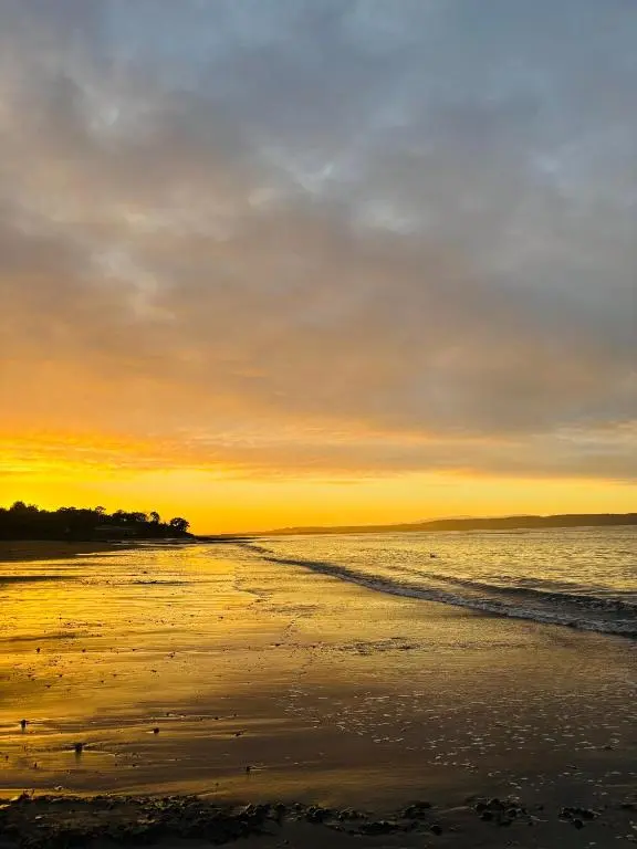 a sunset on a beach with the ocean at Bluebell Cottage in Nairn