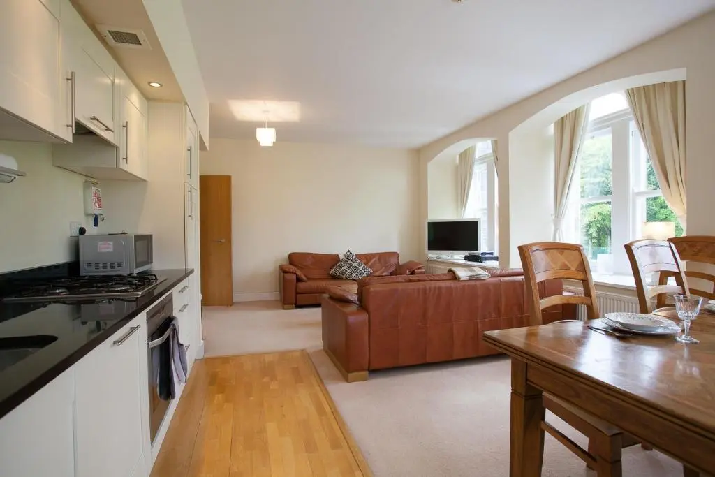 a kitchen and a living room with a couch at Old School Apartments Highland Club in Fort Augustus