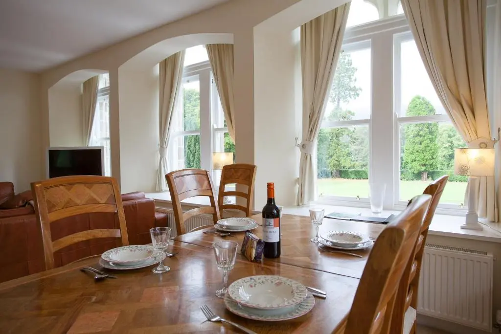 a dining room with a table with a bottle of wine at Old School Apartments Highland Club in Fort Augustus