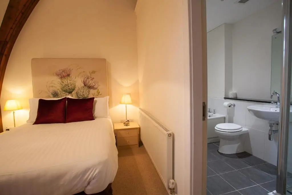 a bedroom with a bed and a toilet and a sink at Old School Apartments Highland Club in Fort Augustus