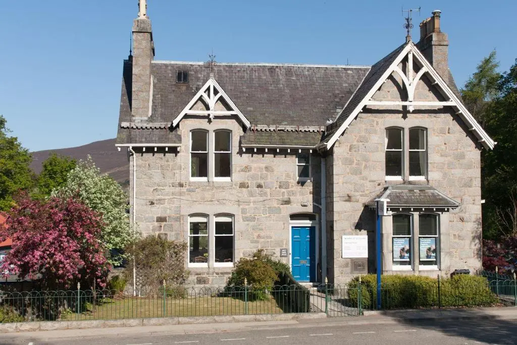 an old stone house with a blue door at Auld Bank House in Braemar