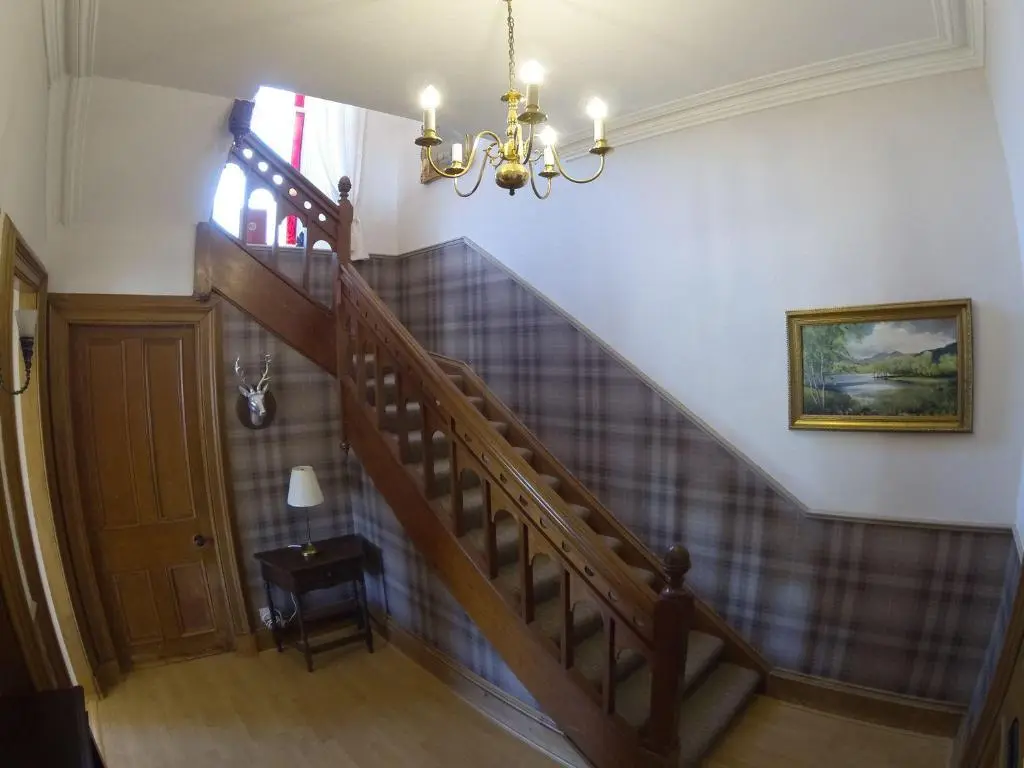 a staircase in a home with a chandelier at Auld Bank House in Braemar