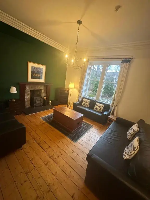 a living room with a couch and a fireplace at Auld Bank House in Braemar