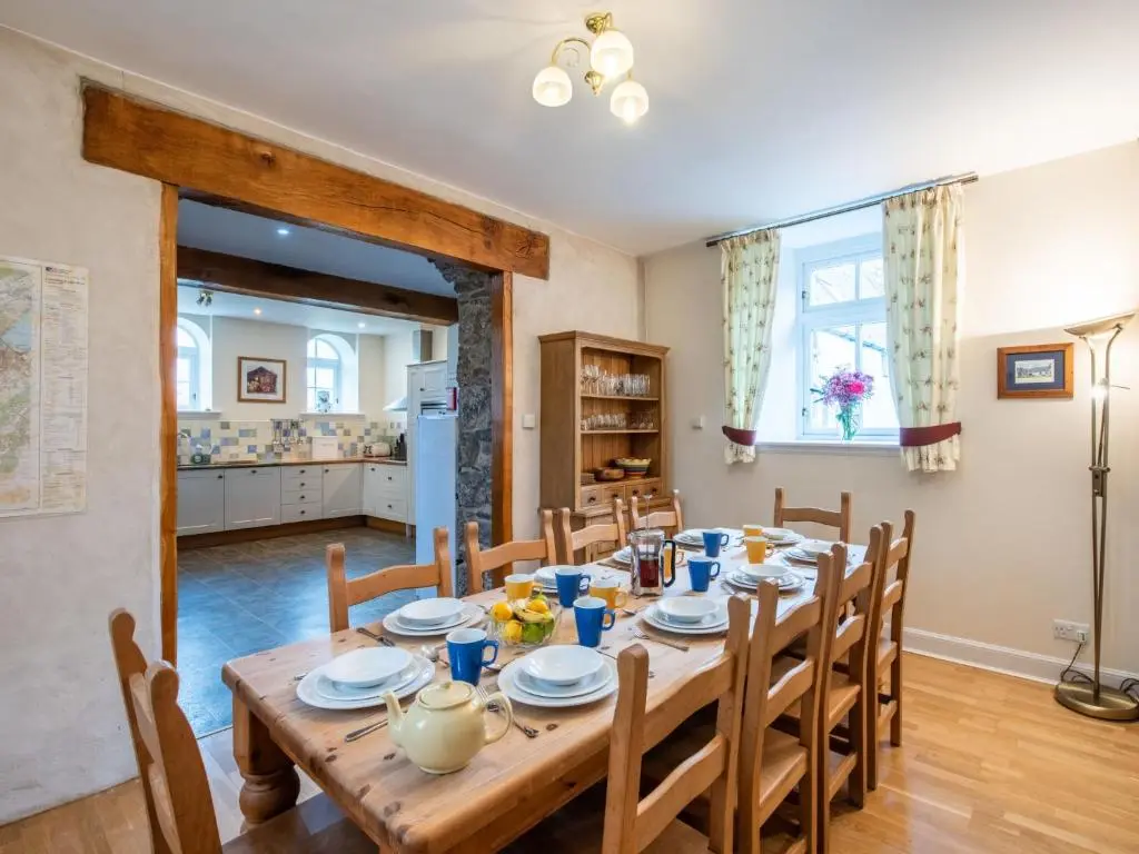 a dining room and kitchen with a wooden table and chairs at Holiday Home Corrimony View by Interhome in Drumnadrochit