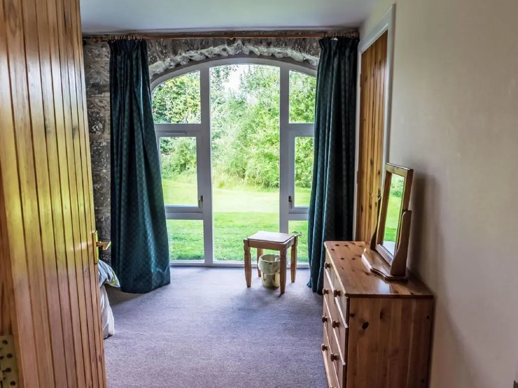 a room with a window and a dresser with a mirror at Holiday Home Corrimony View by Interhome in Drumnadrochit