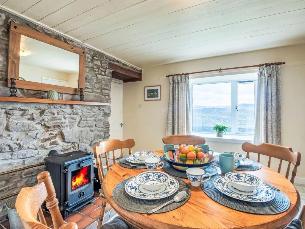 a dining room with a table and a wood stove at Holiday Home Bunloit Farmhouse by Interhome in Drumnadrochit