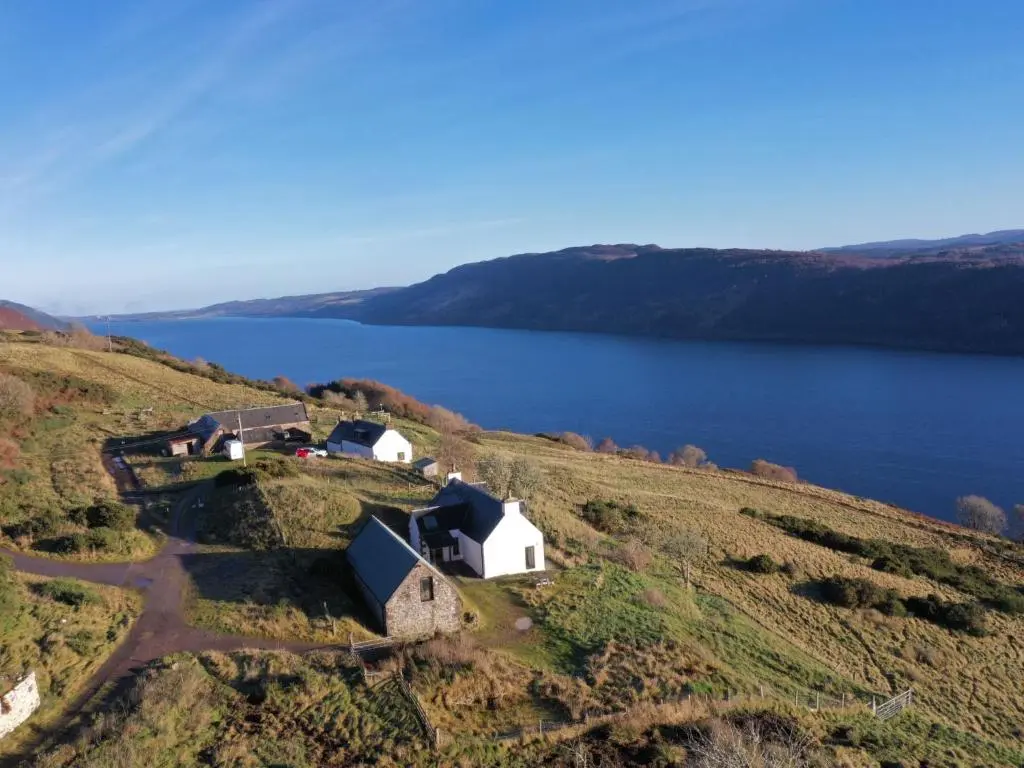 an aerial view of a farm on a hill next to a lake at Holiday Home Bunloit Farmhouse by Interhome in Drumnadrochit