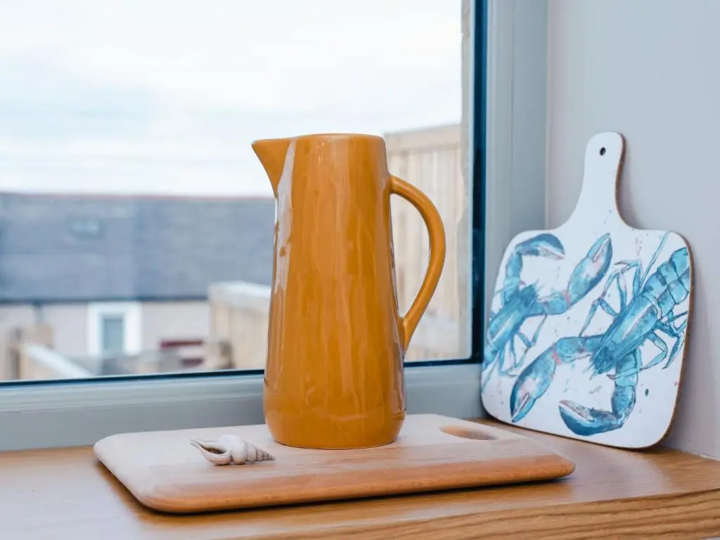 an orange jug and a vase on a window sill at Holiday Home Cooriedoon by Interhome in Hopeman