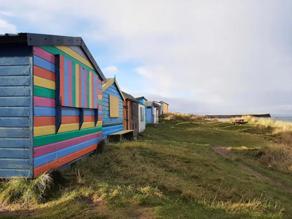 a row of colorful beach huts on the beach at Holiday Home Cooriedoon by Interhome in Hopeman