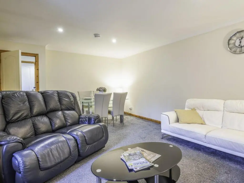 a living room with a couch and a table at Apartment Pitgaveny Apartment by Interhome in Lossiemouth