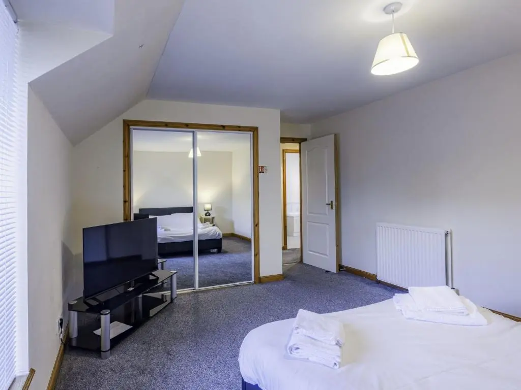 a bedroom with two beds and a mirror at Apartment Pitgaveny Apartment by Interhome in Lossiemouth