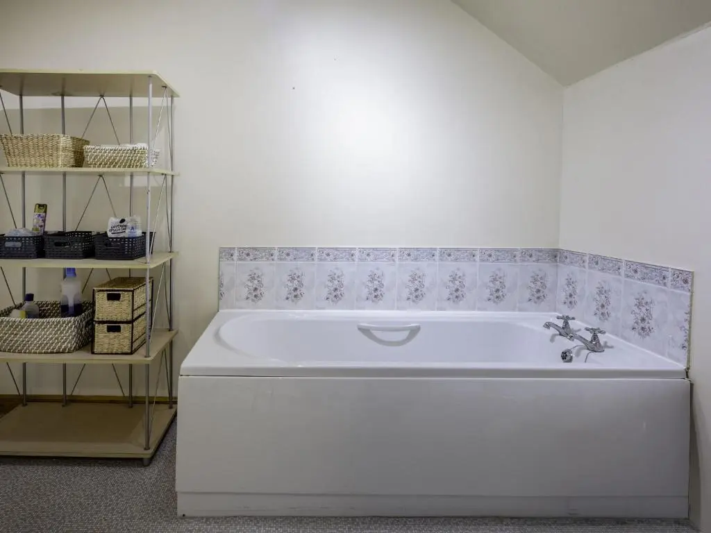 a white bath tub in a room with a shelf at Apartment Pitgaveny Apartment by Interhome in Lossiemouth
