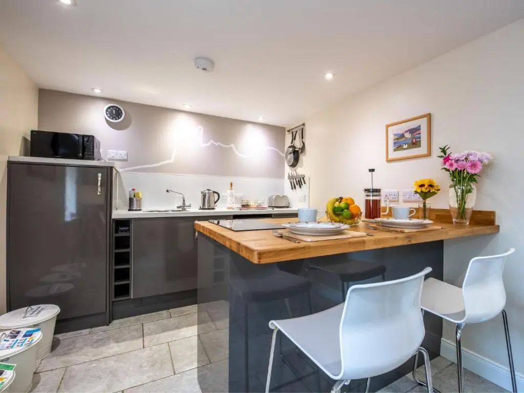 a kitchen with a wooden counter and white chairs at Holiday Home Wayside Bothy by Interhome in Drumnadrochit