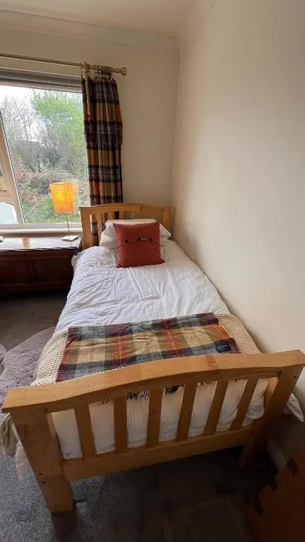 a wooden bed in a room with a window at Beautiful Highland Sanctuary in Embo