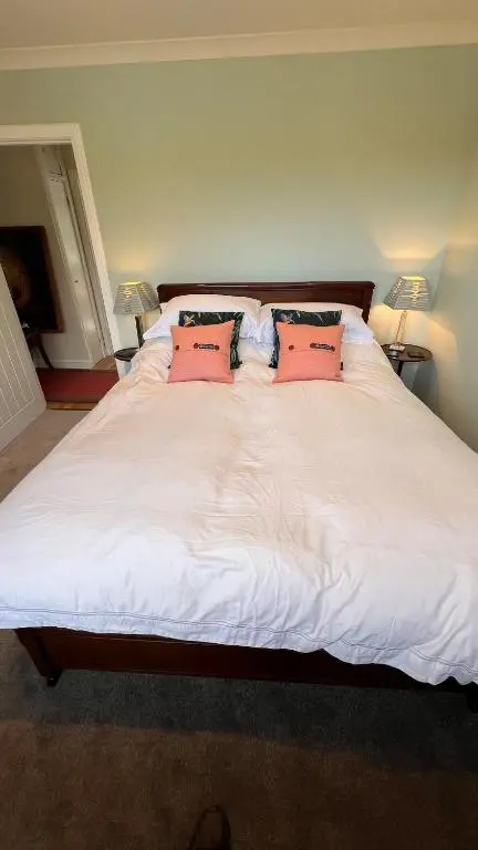 a large white bed with two pink pillows on it at Beautiful Highland Sanctuary in Embo