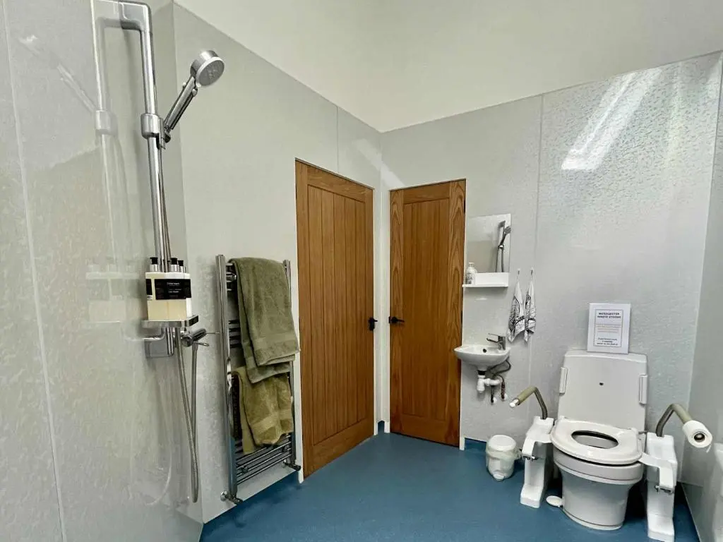 a small bathroom with a toilet and a shower at Ardachy Riverside Accessible One bedroom Holiday let in Fort Augustus