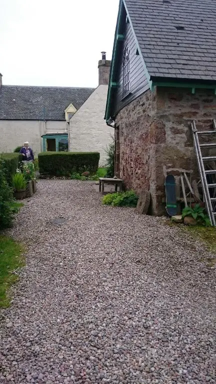 a house with a gravel driveway next to a building at Special Offer, Cosy Cottage Near the Sea in Embo in Embo
