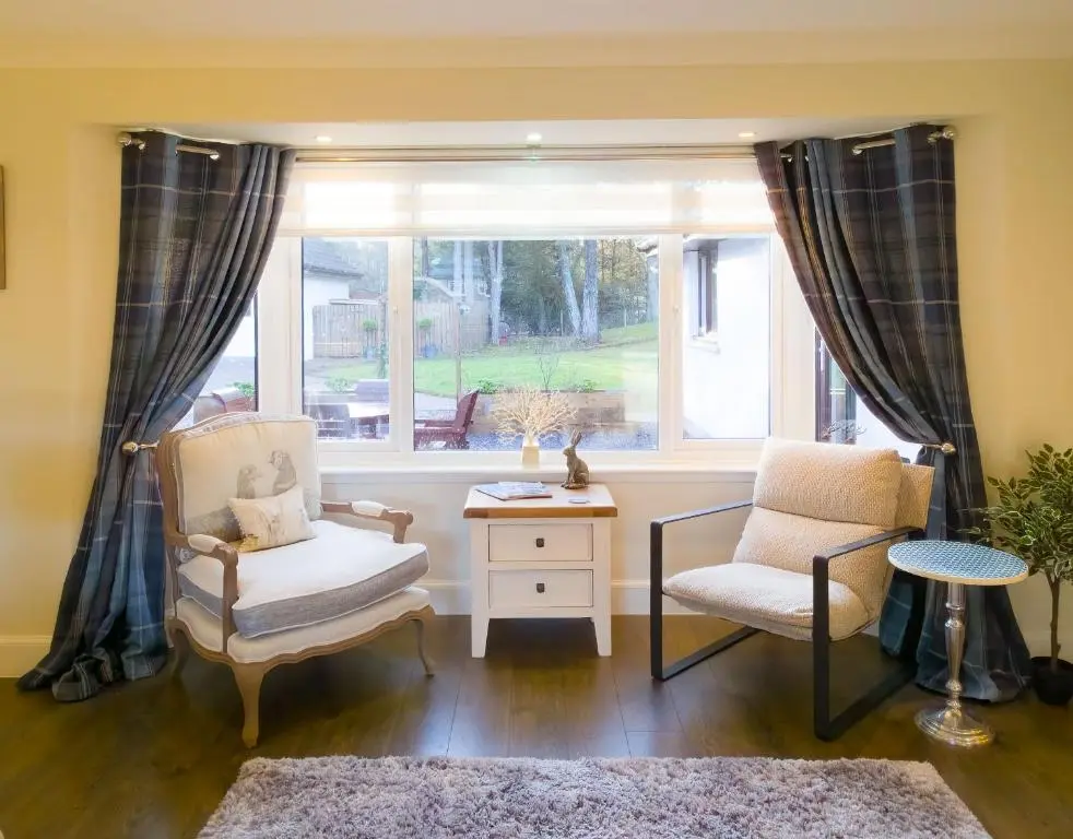 a living room with two chairs and a window at Woodland House in Tomatin