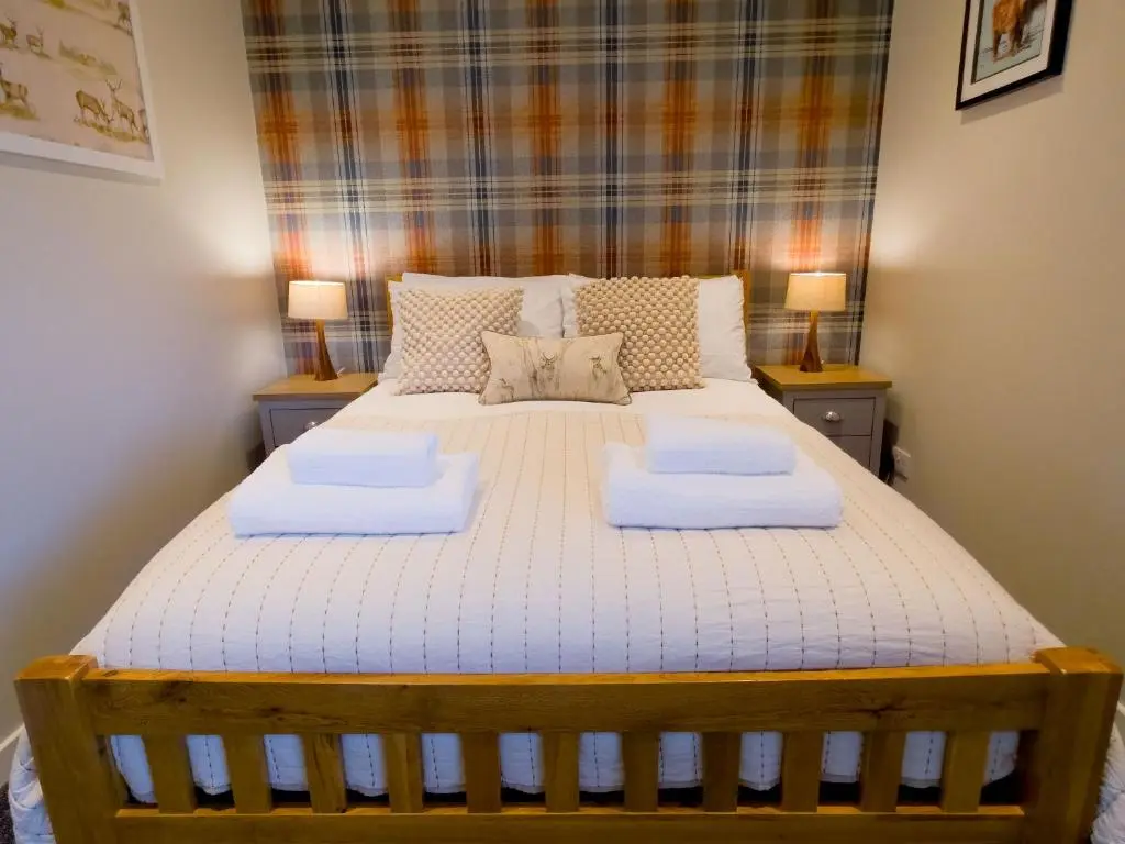 a bedroom with a bed with two towels on it at Woodland House in Tomatin