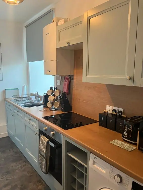 a kitchen with white cabinets and a stove top oven at Toll House in Wick