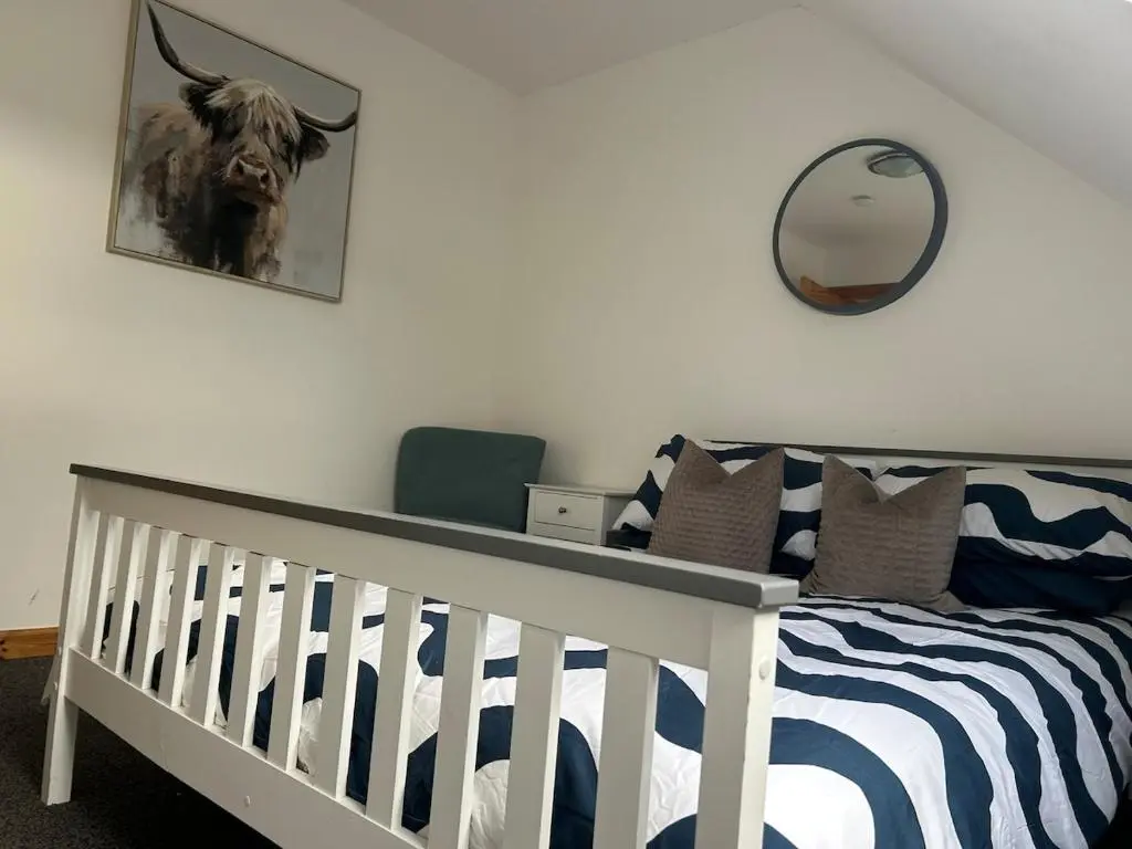 a bedroom with a crib with a mirror and a cow on the wall at Helen's Hoose in Aviemore