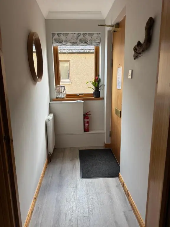an empty hallway with a window and a door at Firth Tides in Nairn