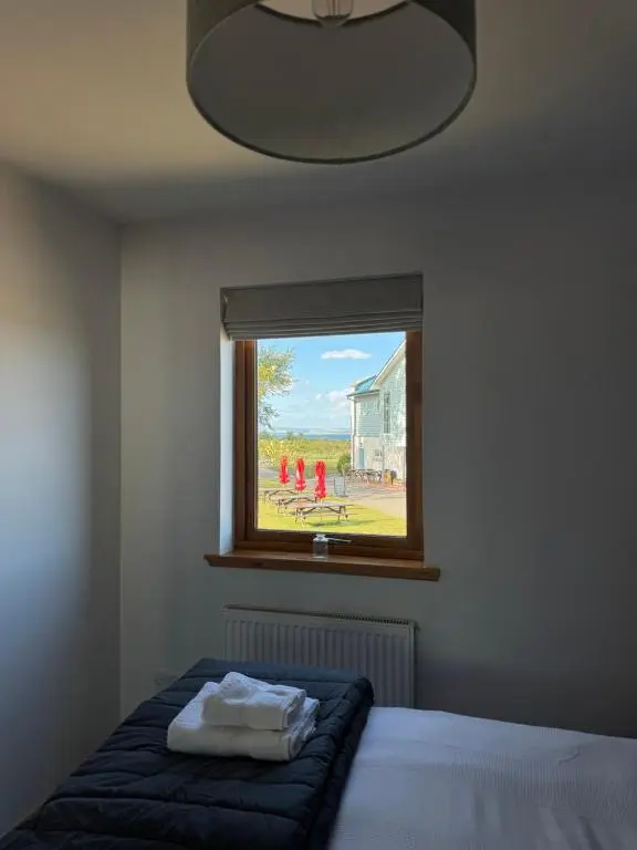 a bedroom with a bed and a window with a painting at Firth Tides in Nairn