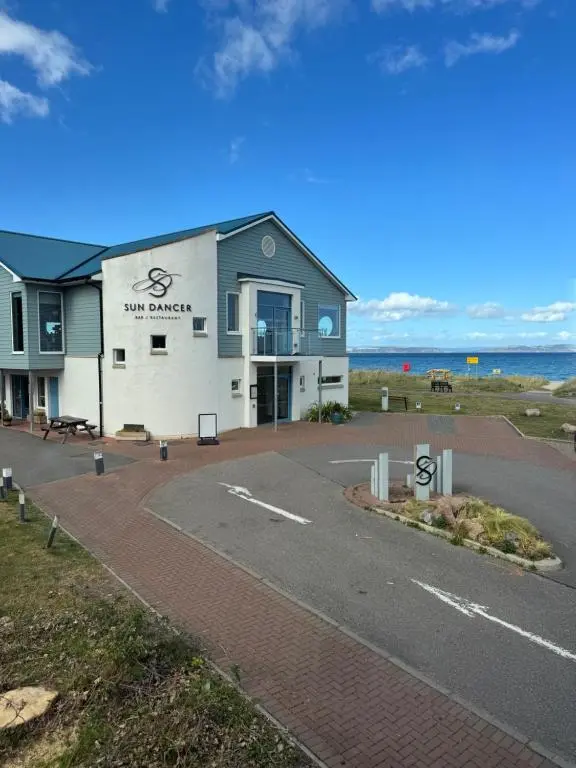 a building on the side of a road next to the ocean at Firth Tides in Nairn
