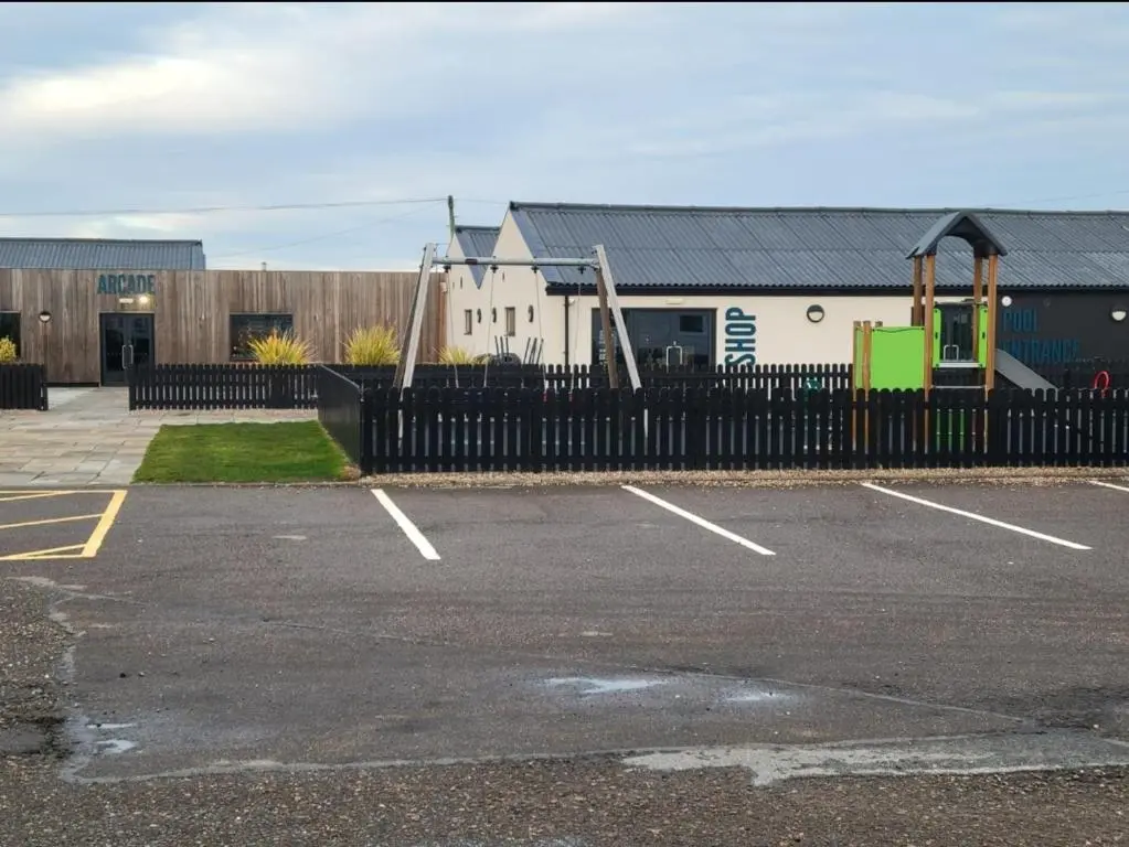 a parking lot with a black fence and a playground at Silversands - Private Caravan Let in Lossiemouth